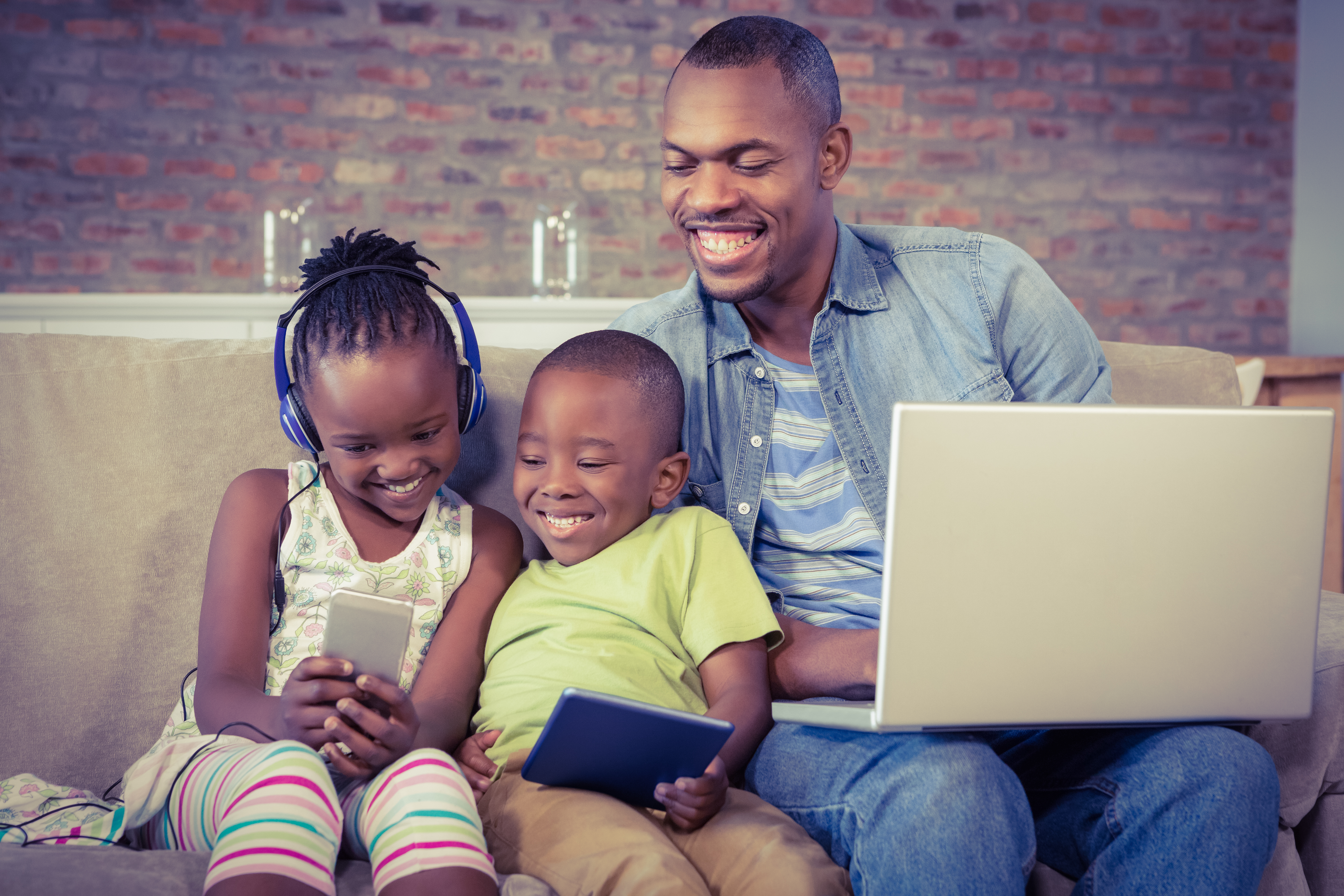 Une famille utilisant un téléphone cellulaire, une tablette et un ordinateur portable