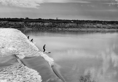 Trois personnes surfent sur une vague dans une rivière.