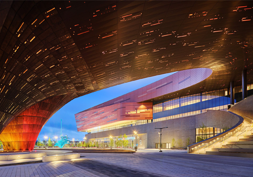 Le dessous d’un large toit en auvent éclairé par de petites lumières orange. Le bâtiment est à l’arrière-plan.