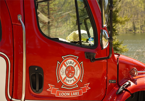 Un gros plan sur la porte passager d’un camion de pompiers portant un emblème représentant des outils de lutte contre les incendies.