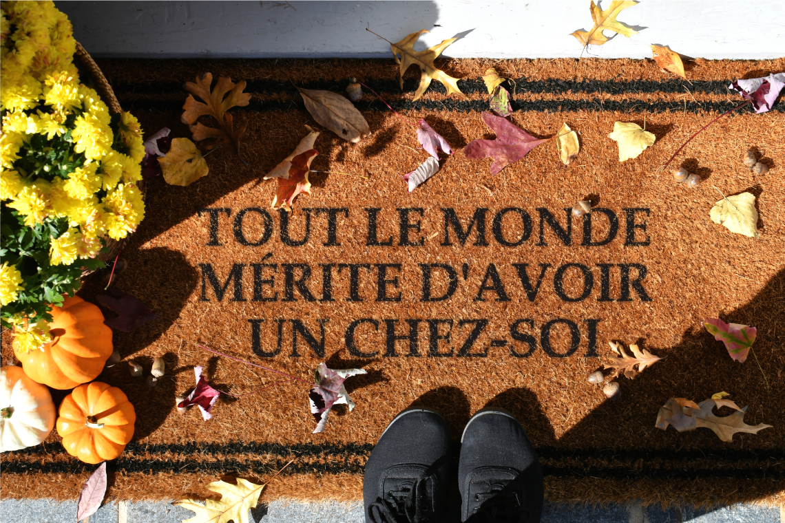 Un tapis sur lequel il est écrit « Tout le monde mérite d’avoir un chez-soi ».